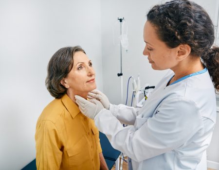 Doctor palpates of fat mature woman's neck for diagnostics of thyroid diseases and hypothyroidism at medical clinic. Thyroid treatment